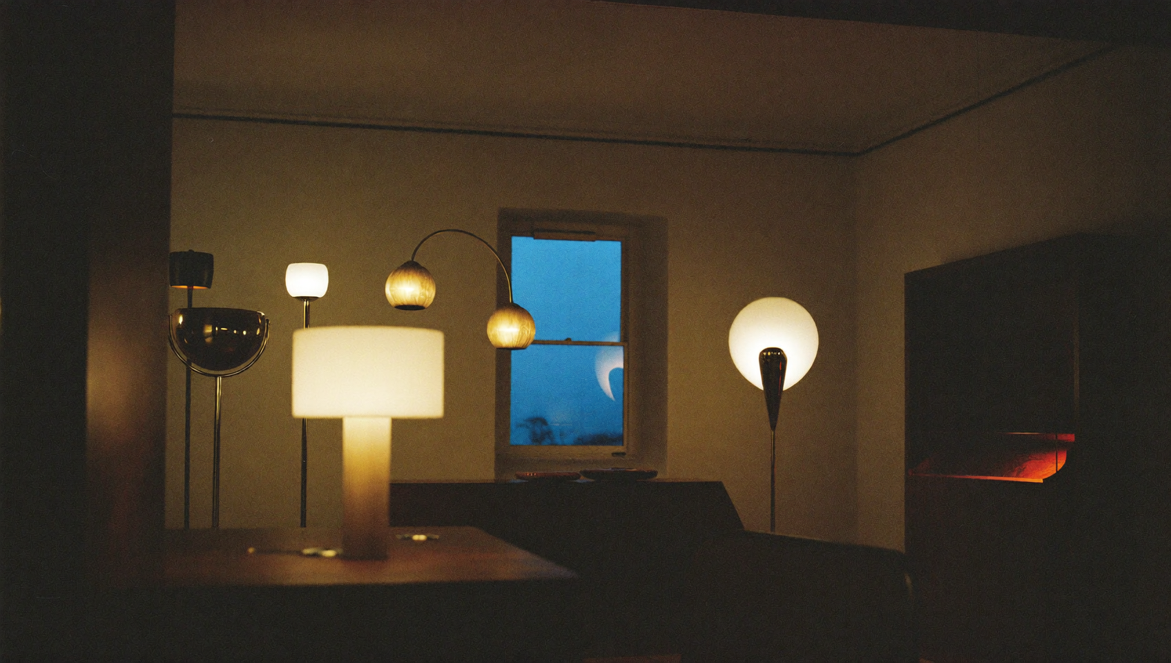 Interno milanese al tramonto con lampade in ottone e vetro accese e una lampada in alabastro in primo piano